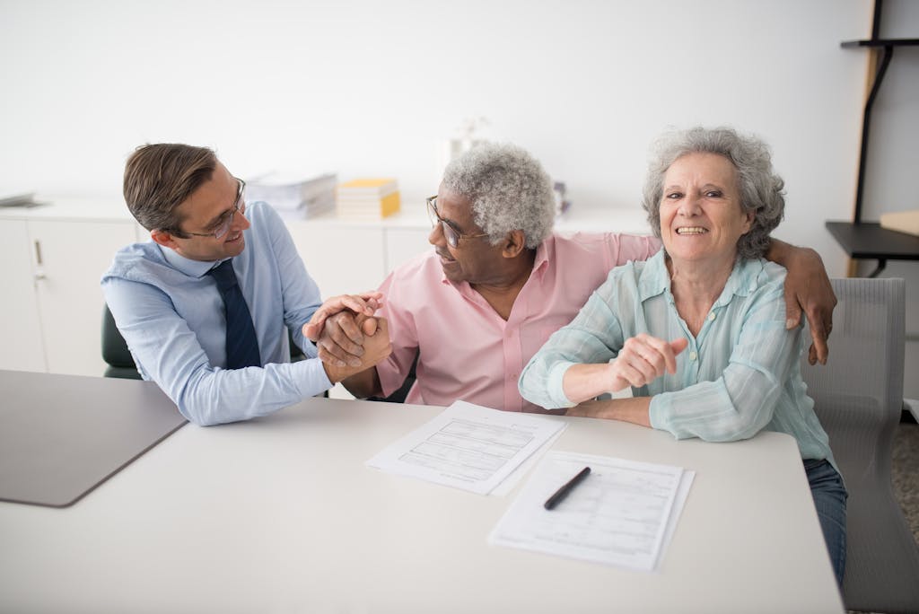 Senior couple in office meeting with consultant, discussing financial documents and smiling.